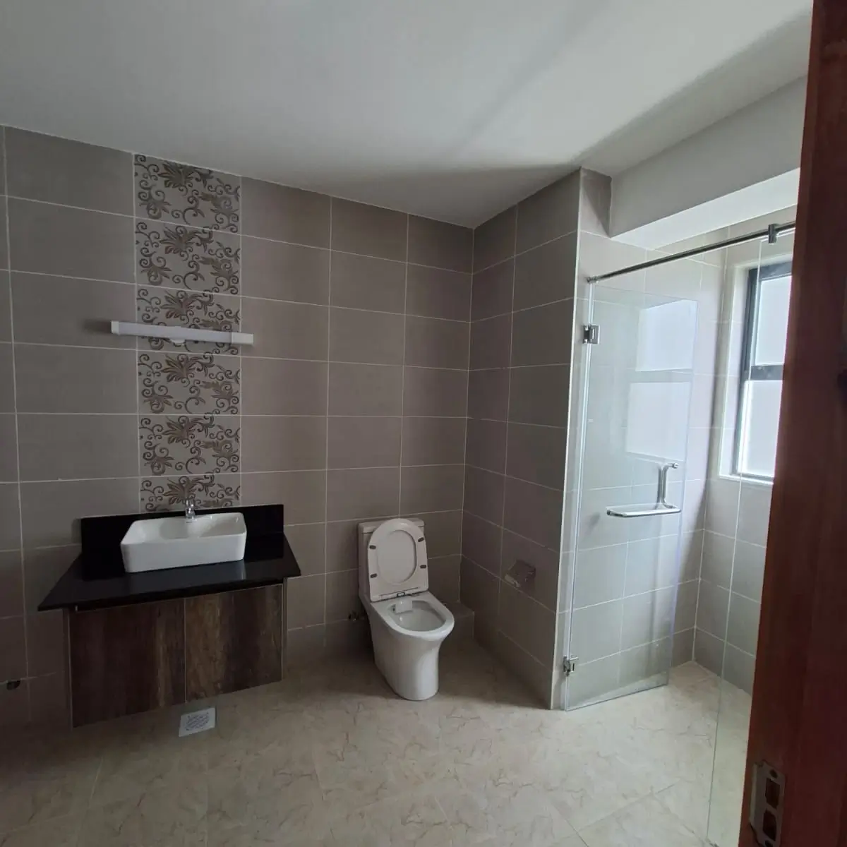 Modern en-suite with vessel sink, toilet, and glass shower