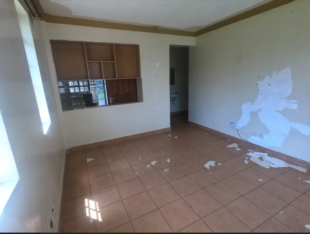 Empty living room with terracotta tiles and wooden shelving.