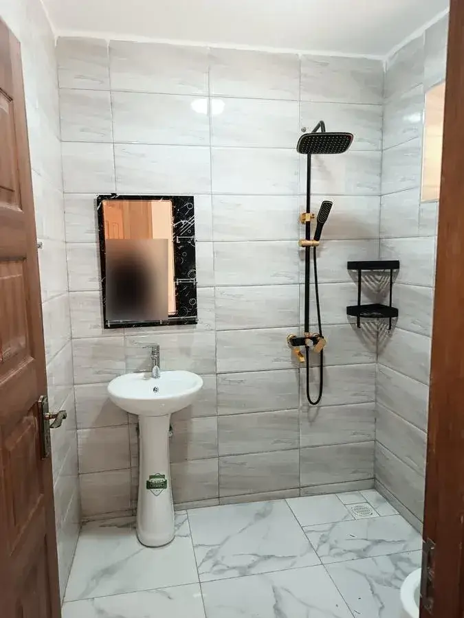 Modern bathroom with pedestal sink, rain shower, marble tile floors
