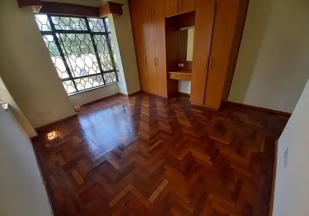Spacious bedroom with herringbone wood flooring and built-in wardrobe