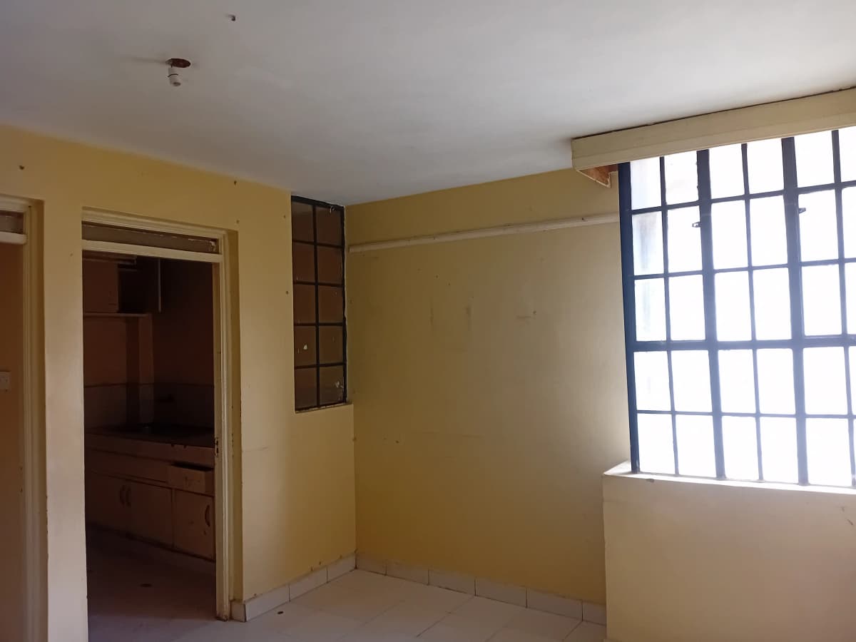 Empty bedroom with yellow walls and barred window