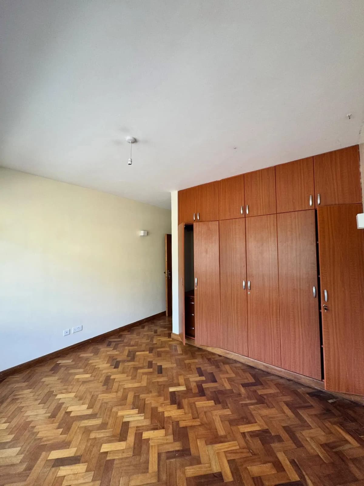 Spacious bedroom with wooden wardrobes and parquet flooring