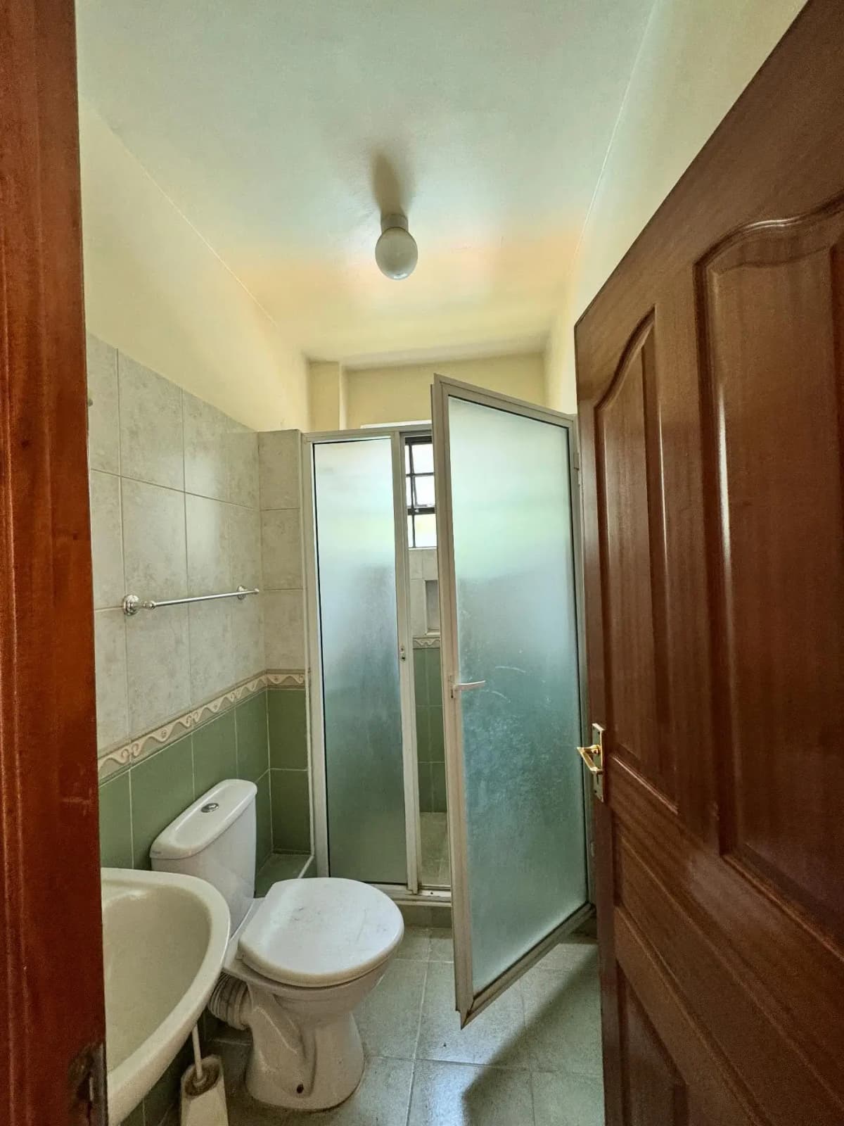 Compact bathroom with toilet, sink, and glass shower enclosure