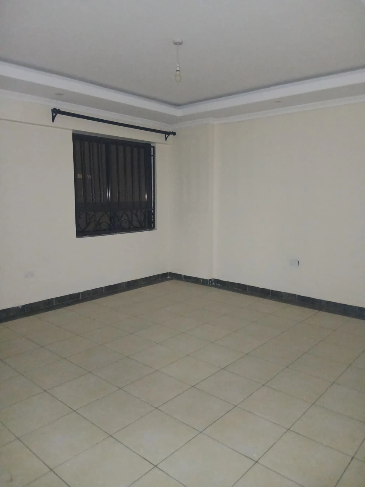 Empty bedroom with tiled flooring and window with black curtains