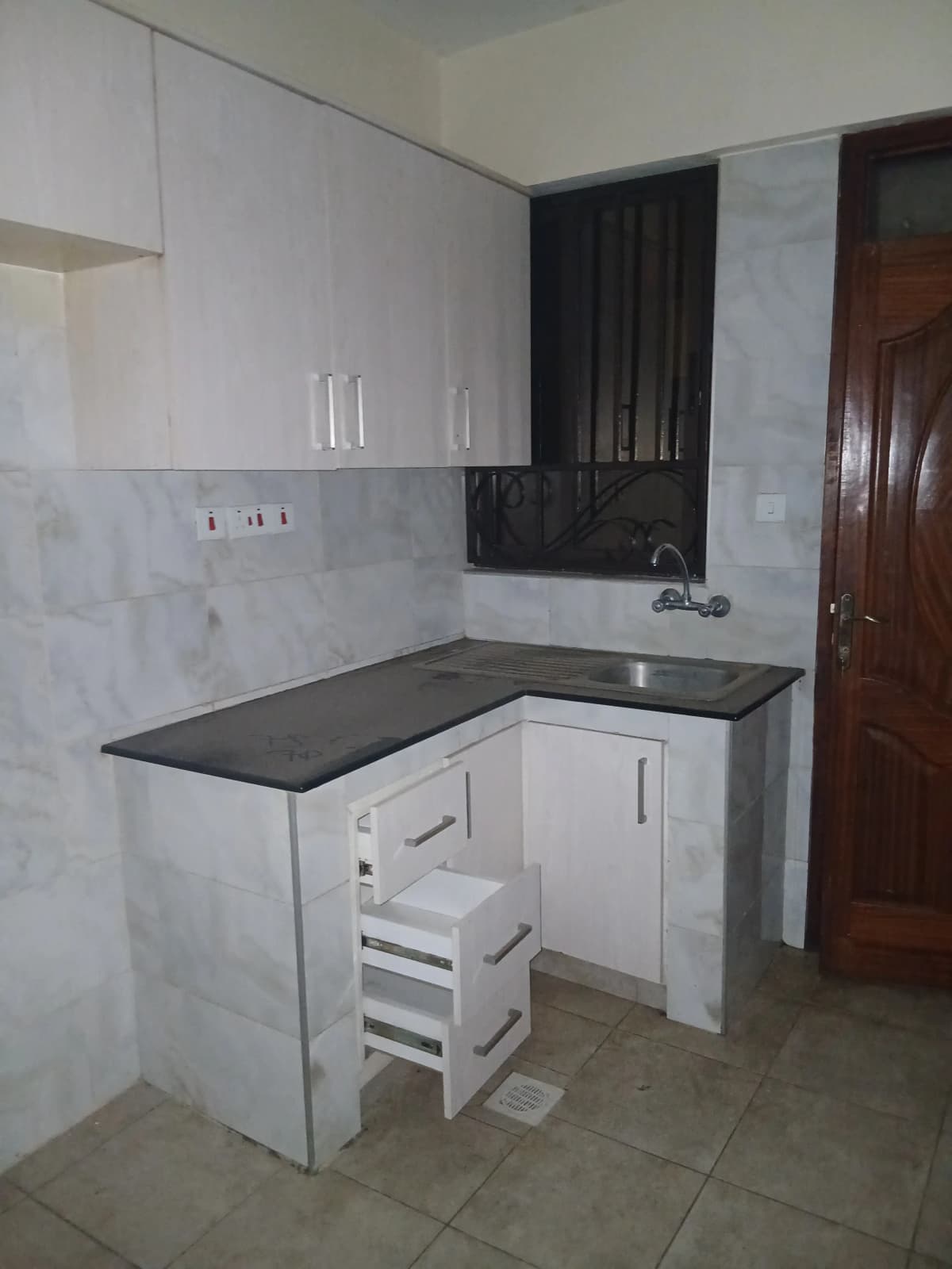 Compact L-shaped kitchen with white cabinets and black countertop
