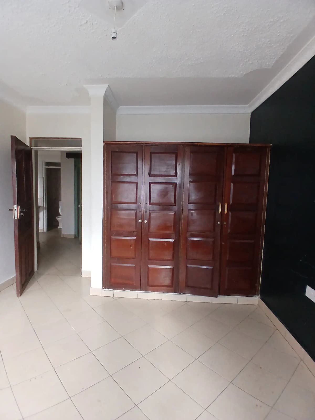 Bedroom with large wooden wardrobe and white tile flooring