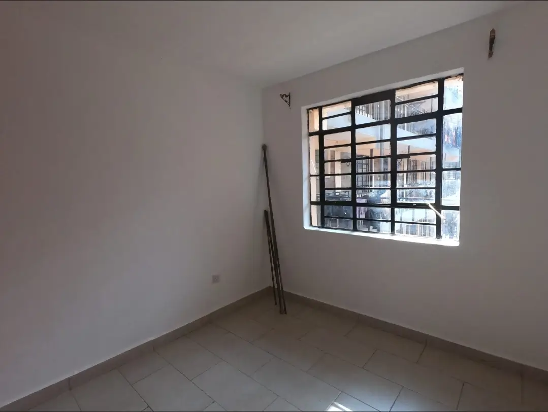 Bright unfurnished bedroom with large window and tiled flooring