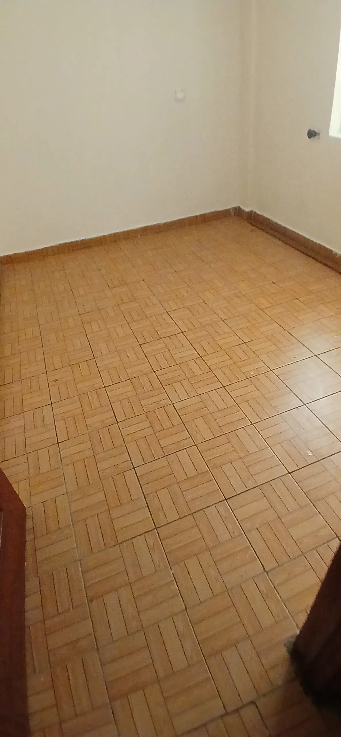 Empty bedroom with herringbone parquet flooring and cream walls