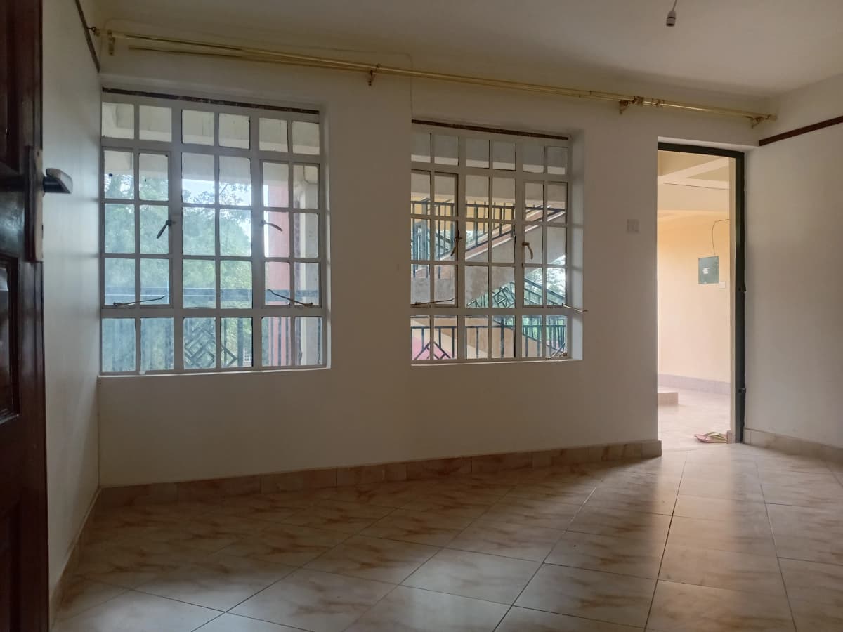 Empty living room with large windows and tiled flooring