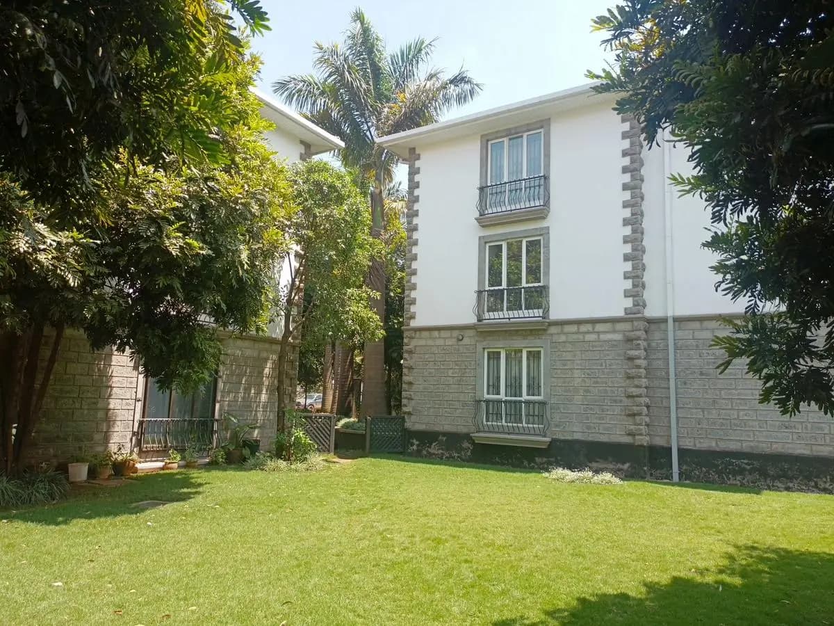 Lush manicured lawn with mature trees and residential building