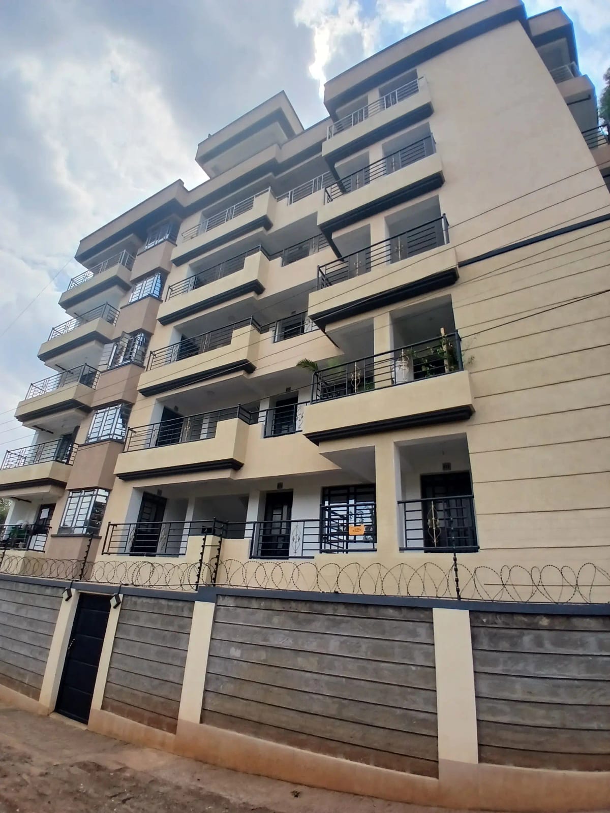 Modern multi-story residential building with balconies and perimeter wall