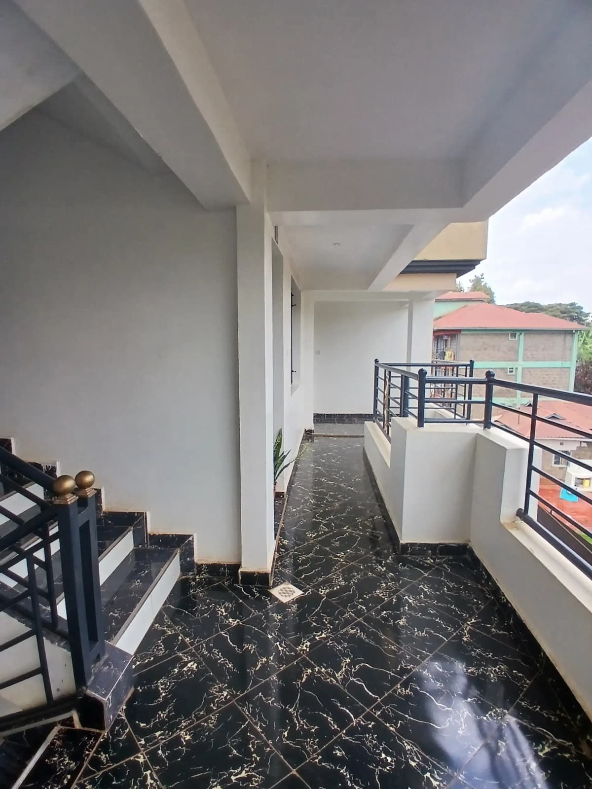Spacious covered balcony with black marble flooring and railing