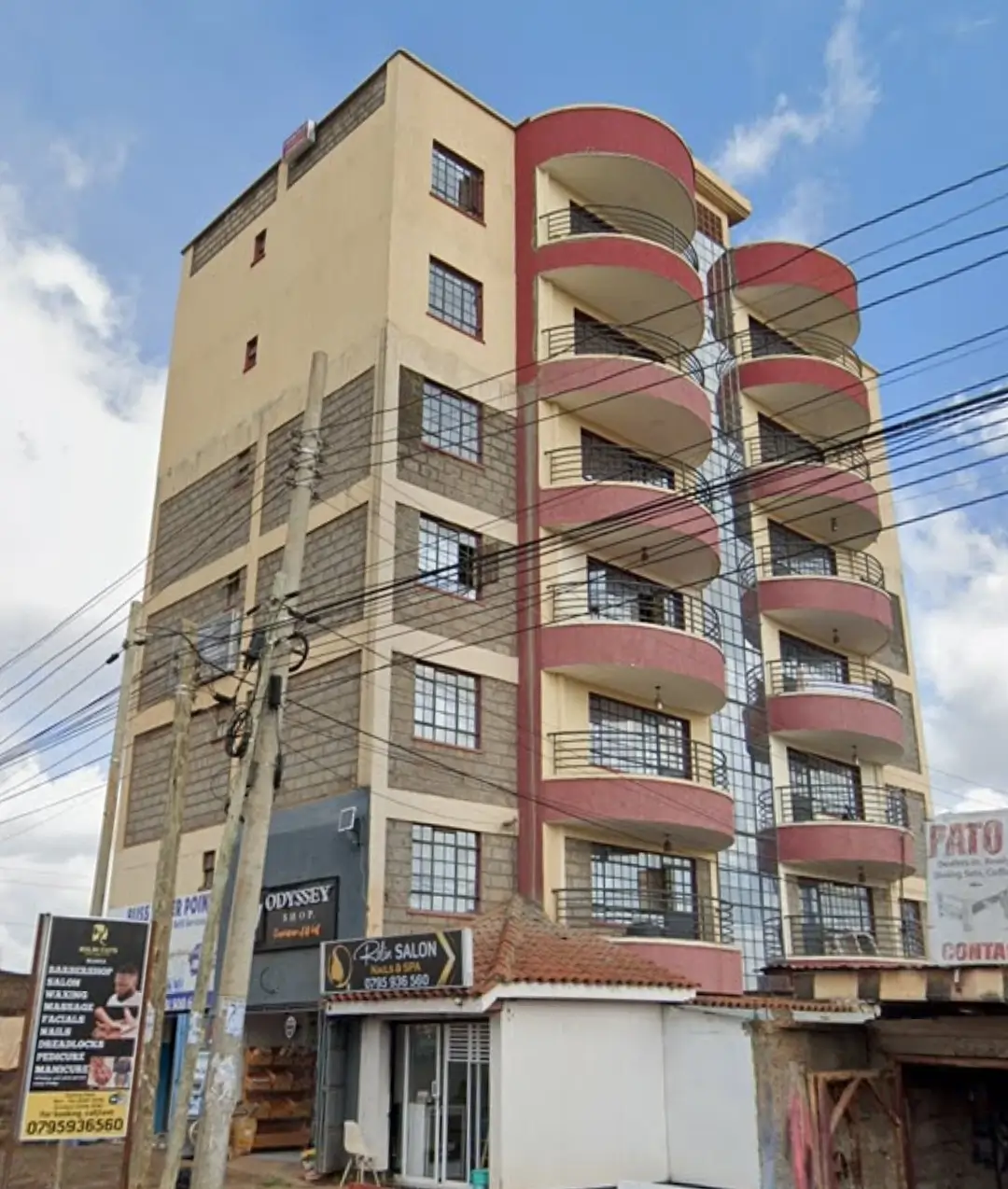 Multi-story residential building with red balconies and street frontage
