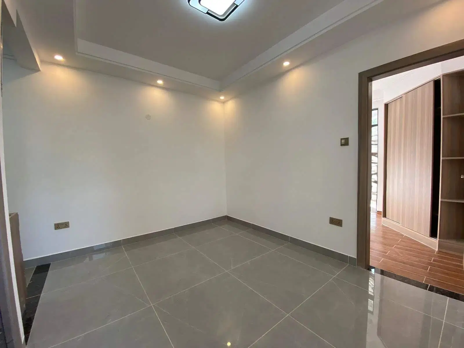 Empty bedroom with gray tile flooring and recessed lighting