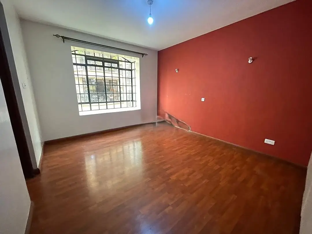 Spacious living room with red accent wall and wooden flooring