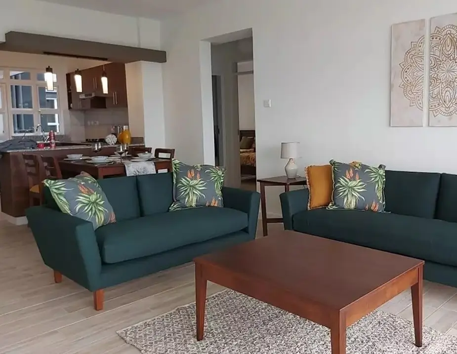 Open-plan living room with teal sofas, wooden coffee table