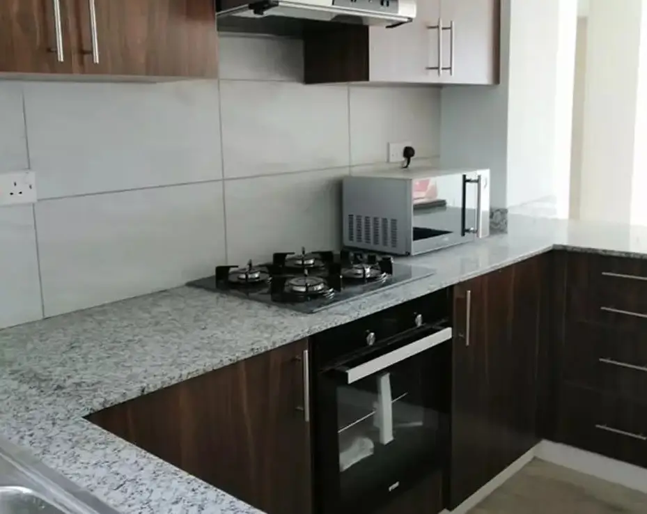 Modern kitchen with granite counters, gas stove, dark cabinetry