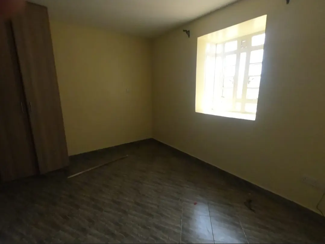 Empty bedroom with wooden flooring and natural window light