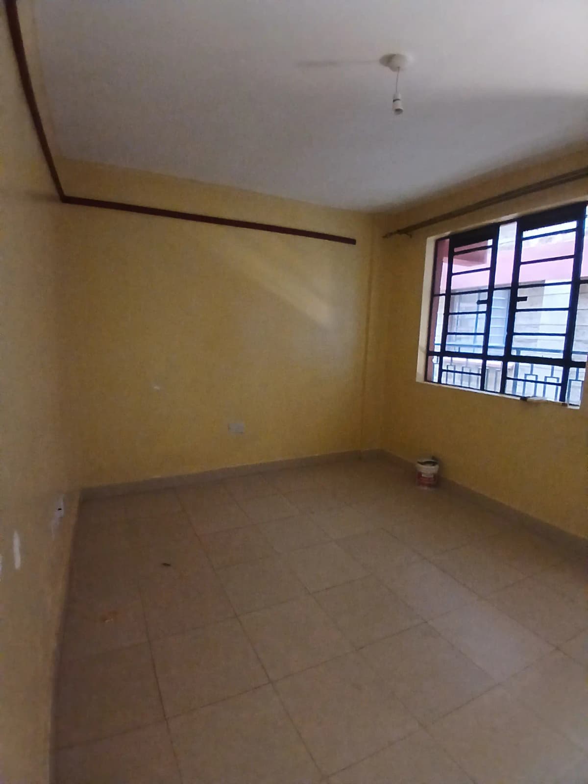 Unfurnished bedroom with yellow walls and barred window