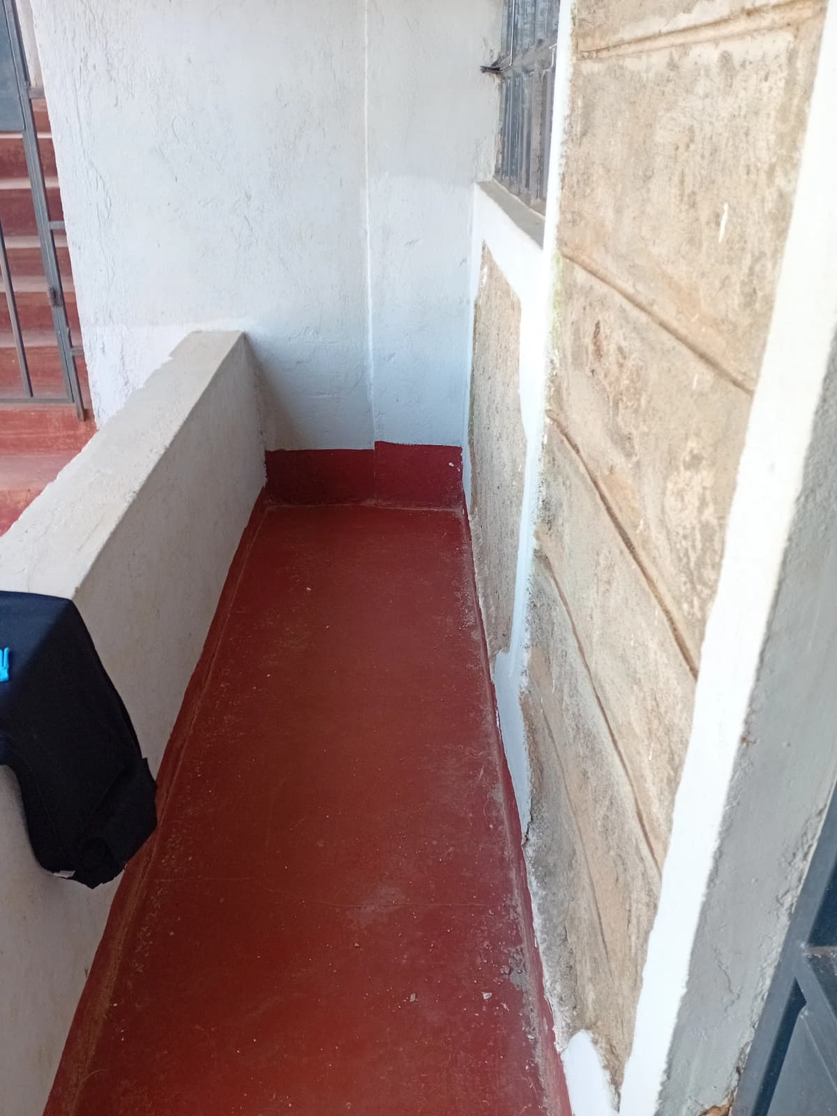 Narrow outdoor balcony or corridor with red tiled floor