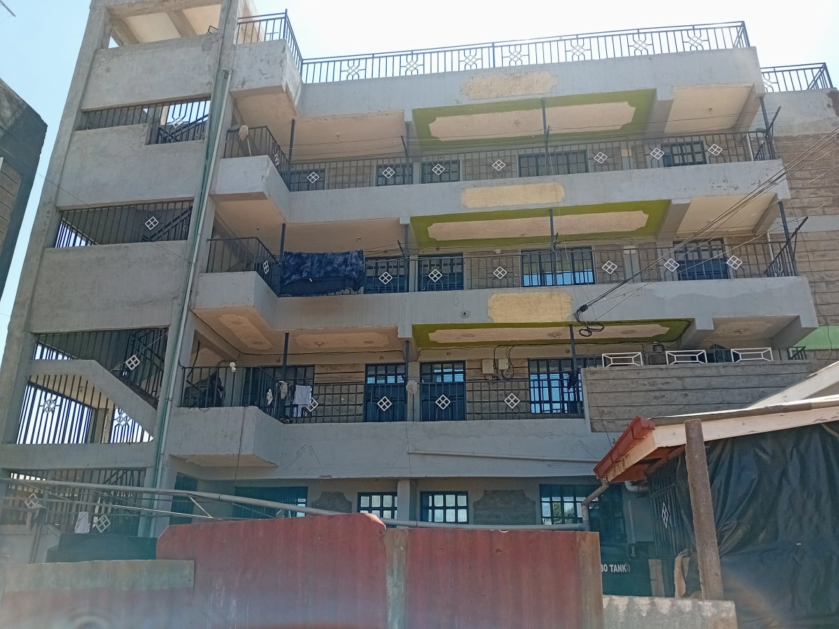 Multi-story residential building facade with balconies and green accents