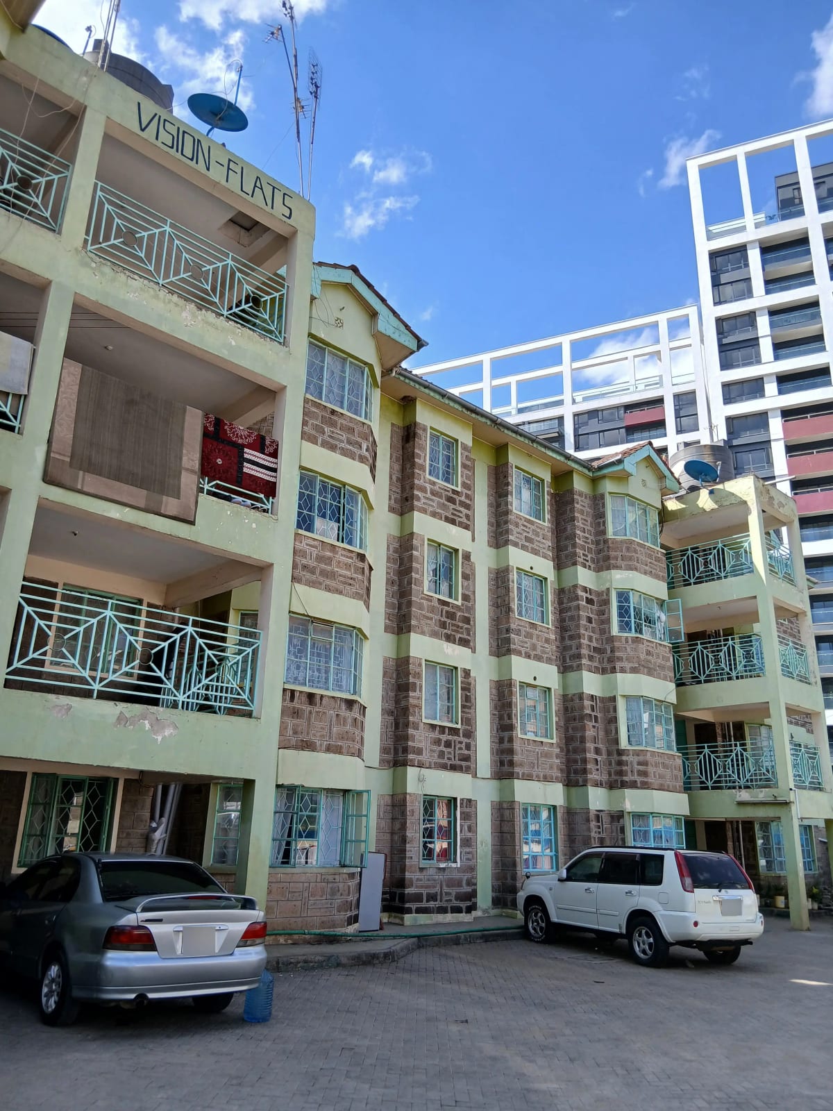 Multi-story residential building facade with parked vehicles