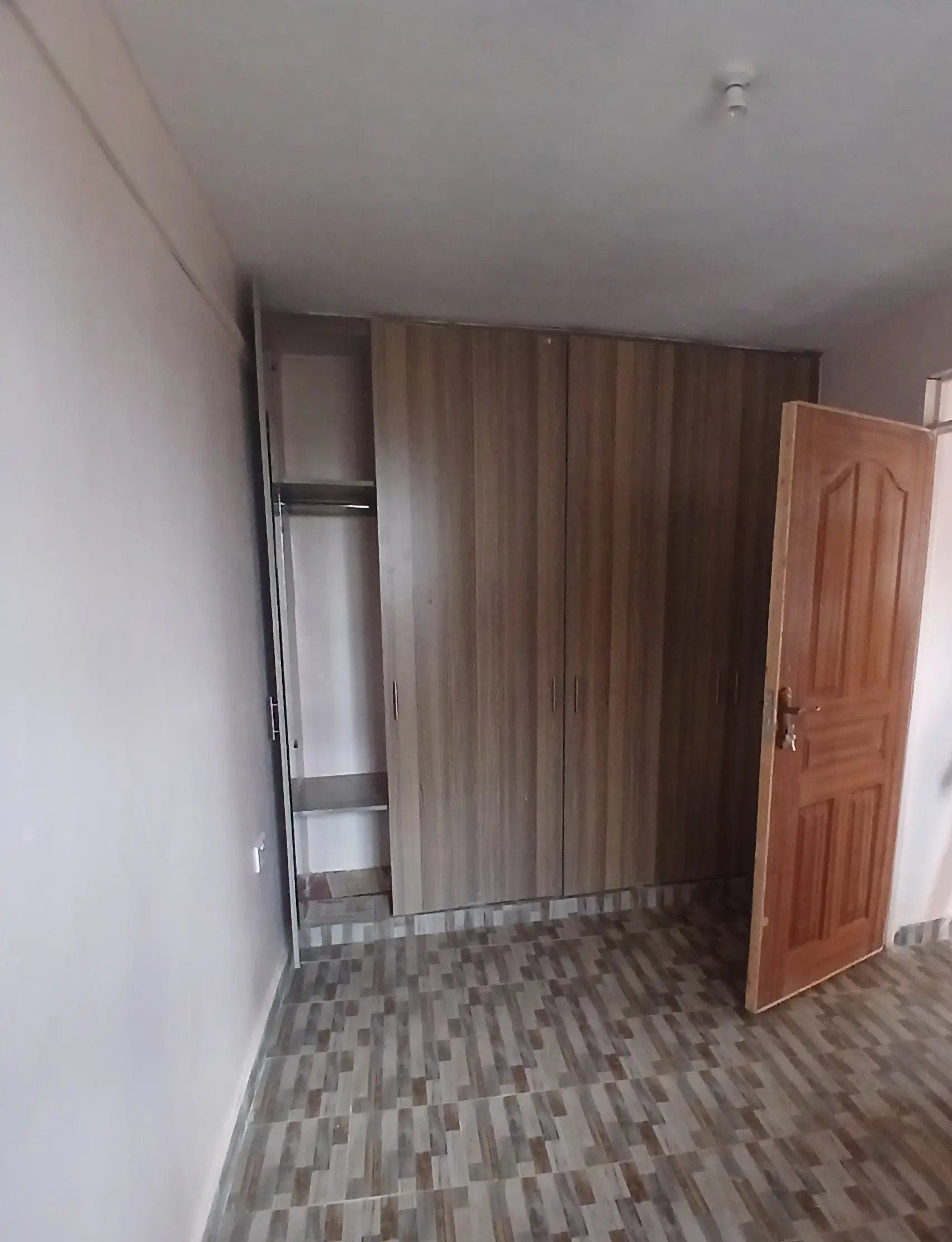 Unfurnished bedroom with built-in wardrobe and wooden door