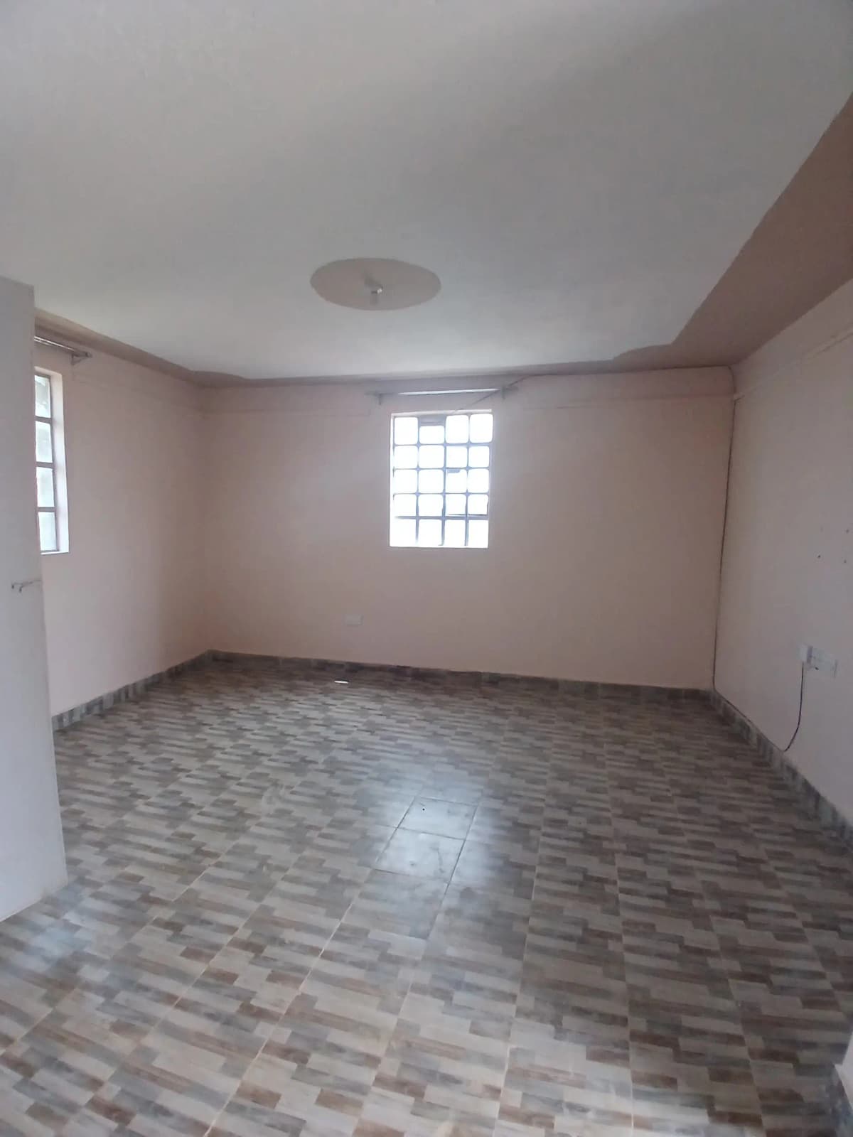 Empty living room with herringbone tile flooring and natural light