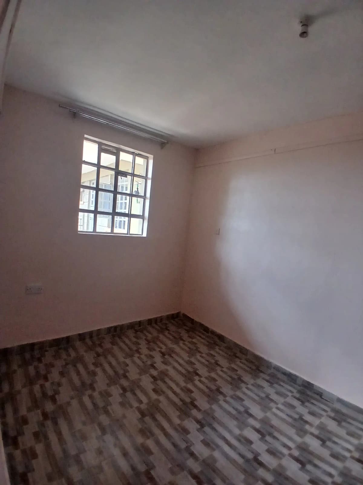 Empty bedroom with barred window and wooden laminate flooring