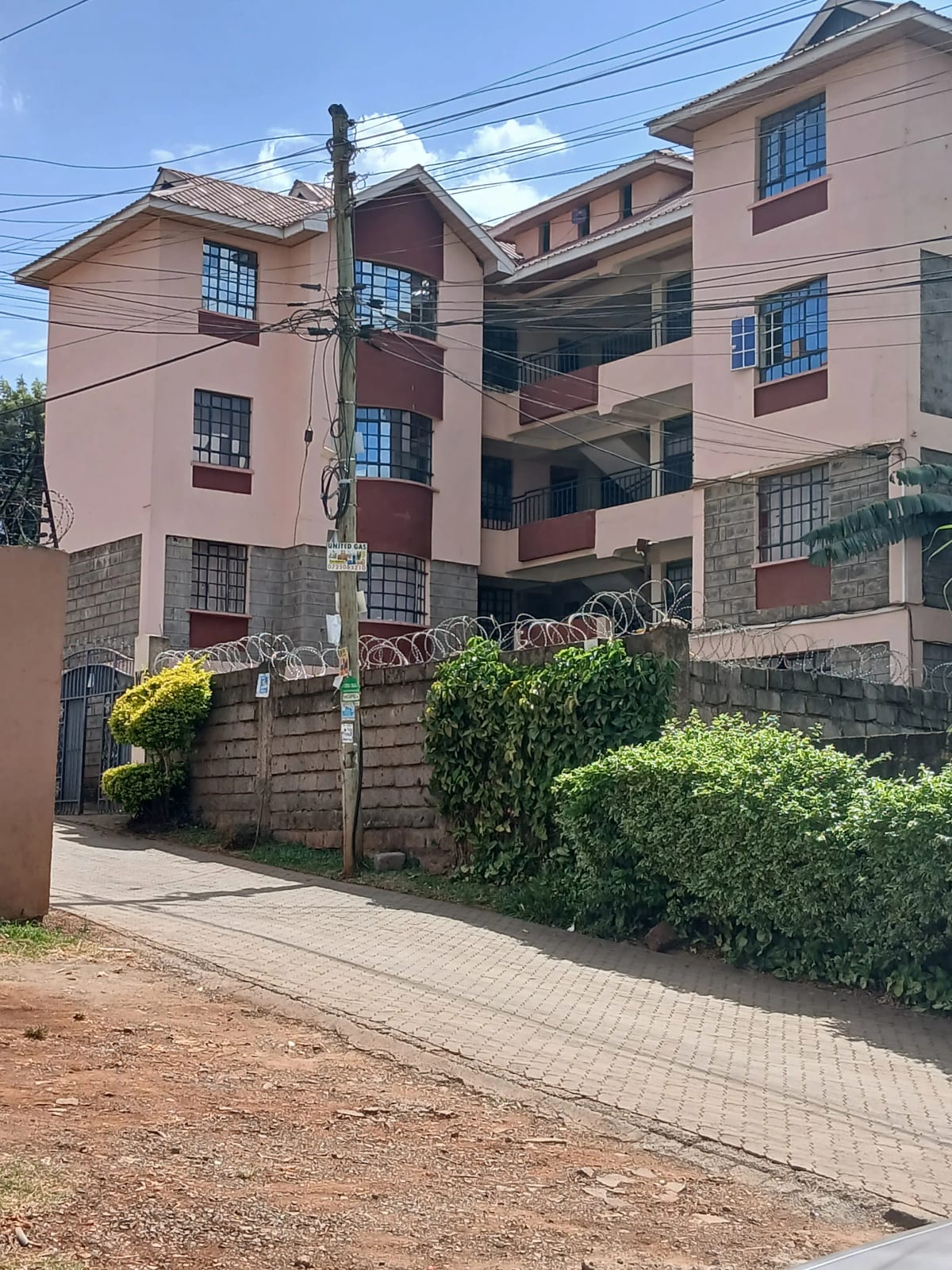 Multi-story residential building with pink facade and landscaped gate