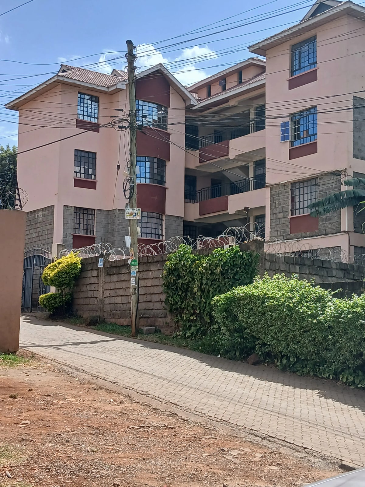 Multi-story residential building with pink facade and landscaped gate