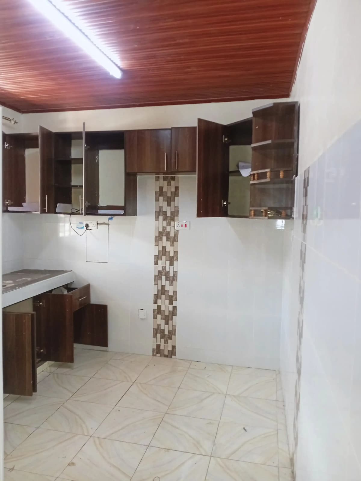 Kitchen with wooden cabinets, tiled backsplash, basic fixtures