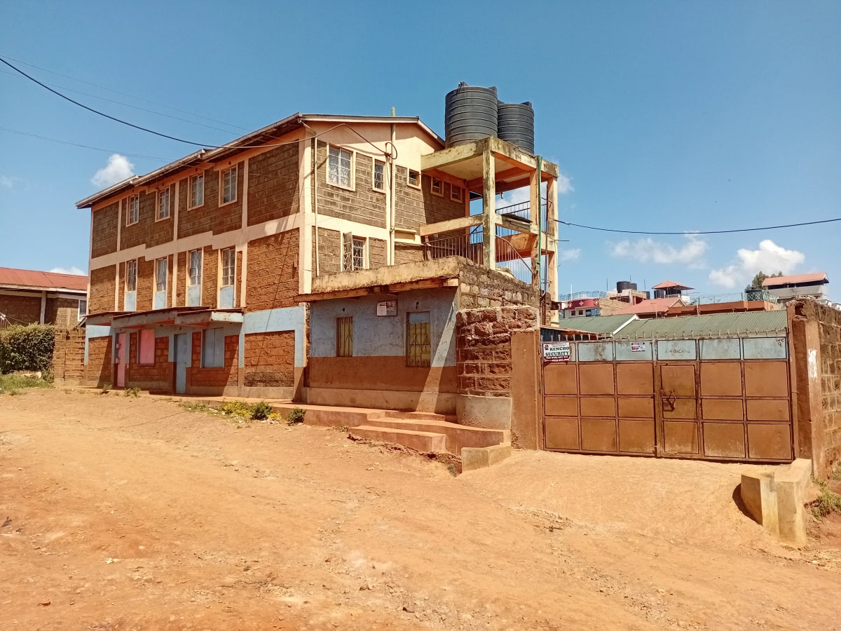 Multi-story brick building with metal gate and compound entrance