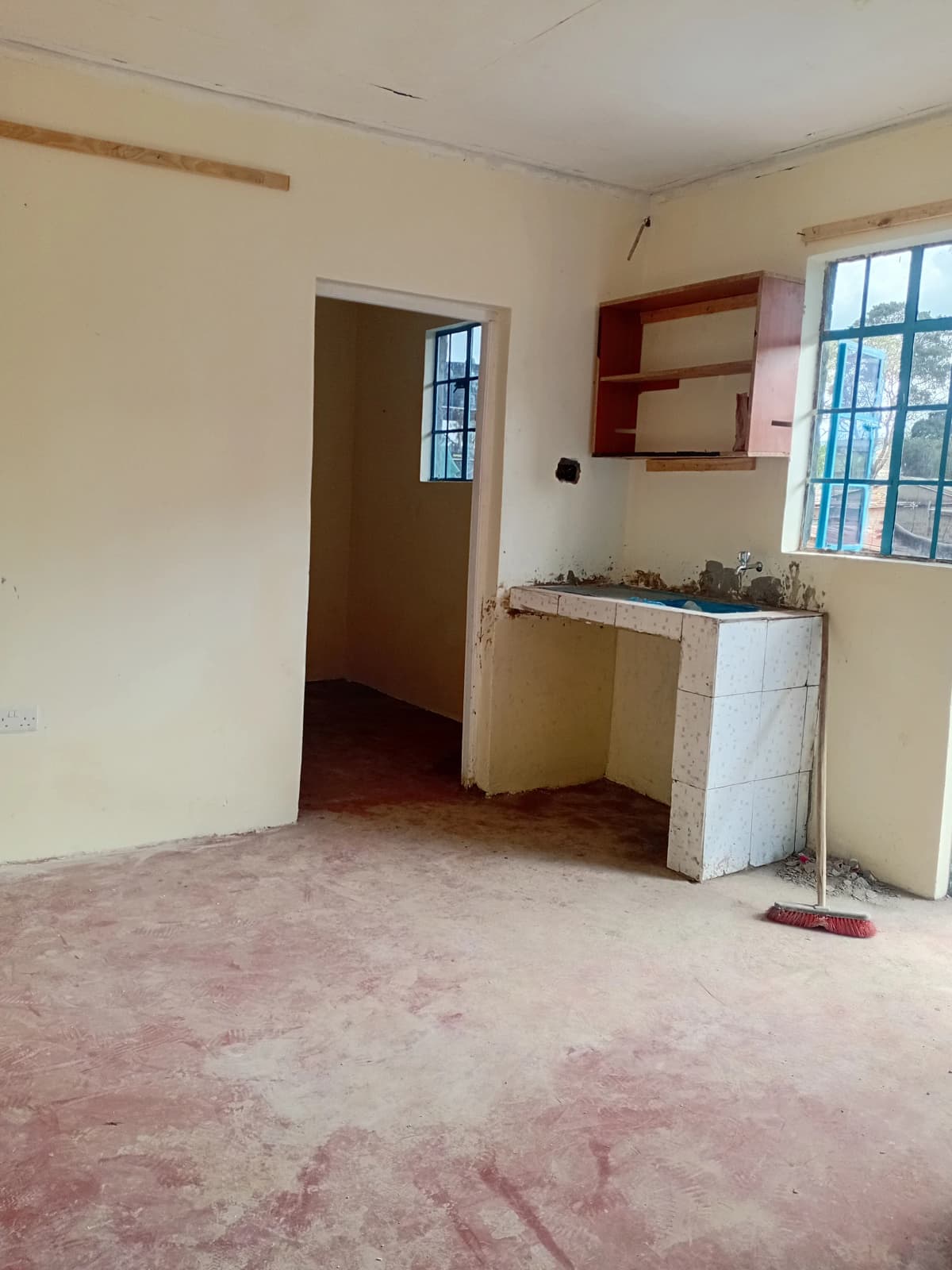Open-plan living area with compact kitchenette and red shelving unit