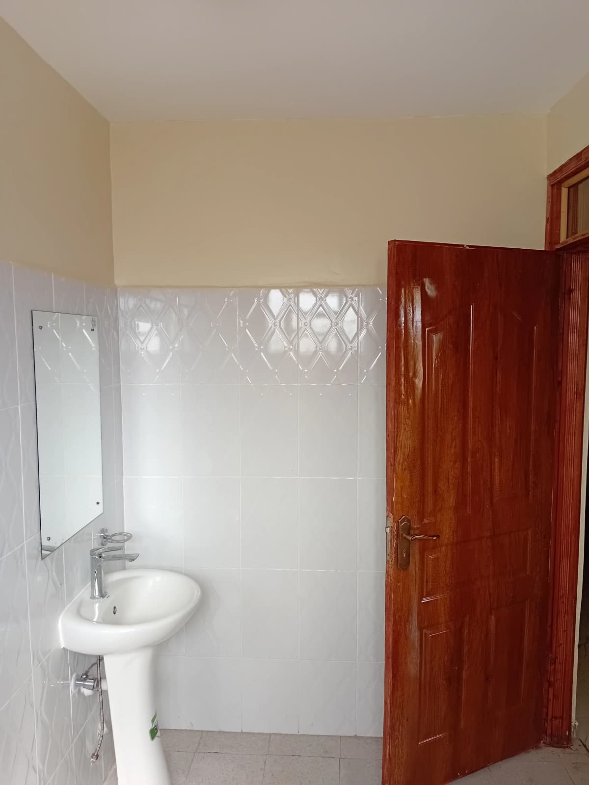 Compact bathroom with pedestal sink and tiled walls