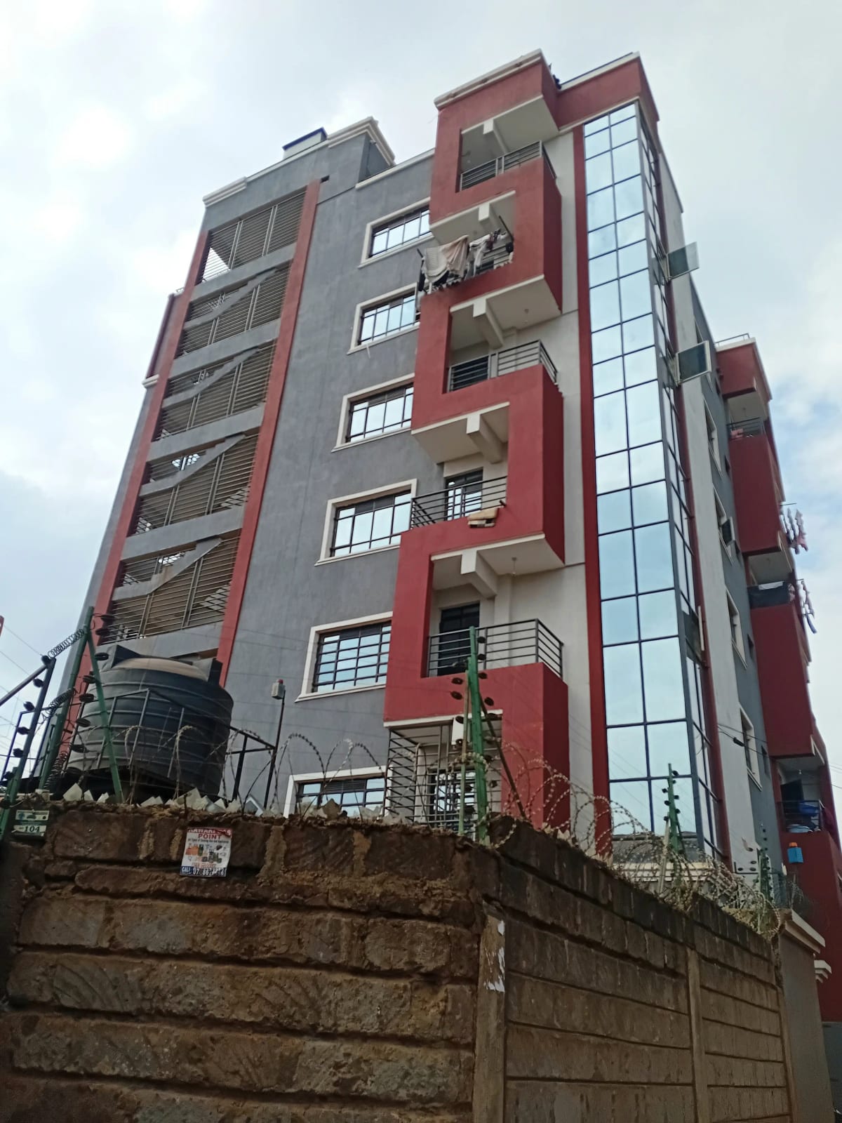 Modern mid-rise residential building with red and gray facade