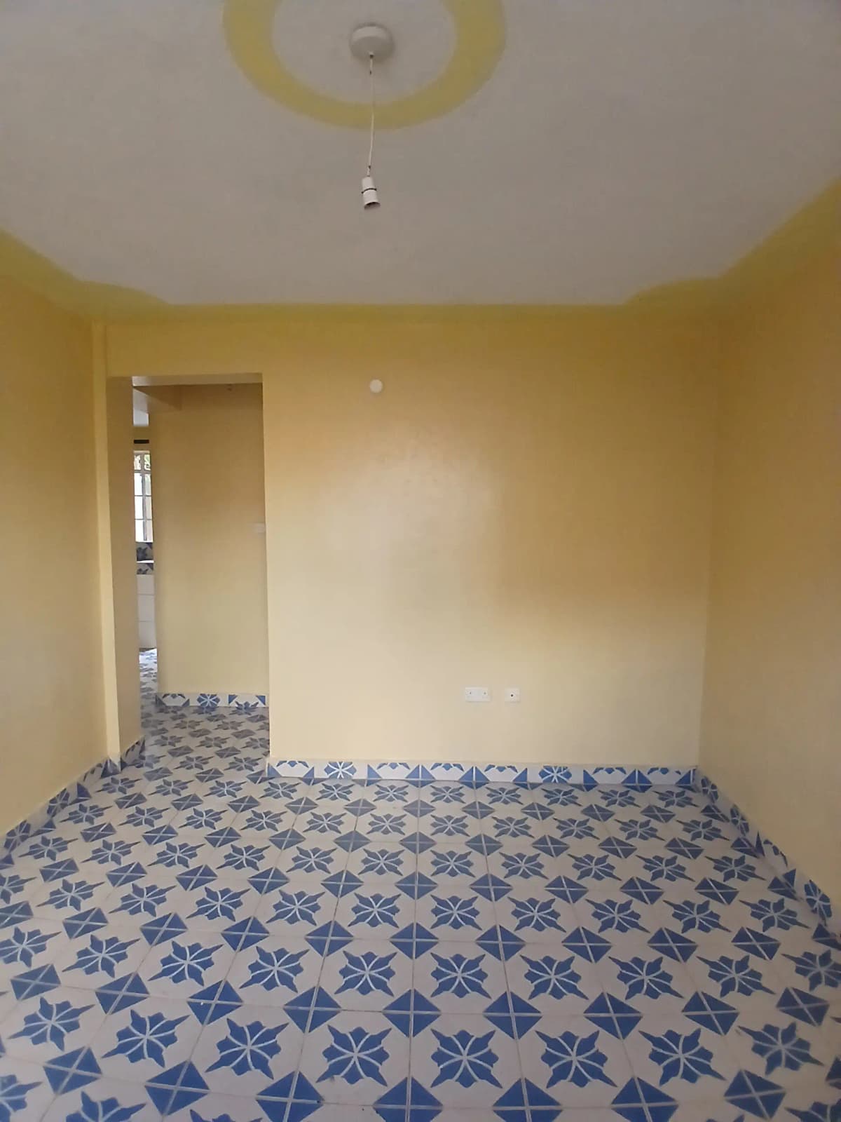 Empty bedroom with blue patterned tile flooring, yellow walls