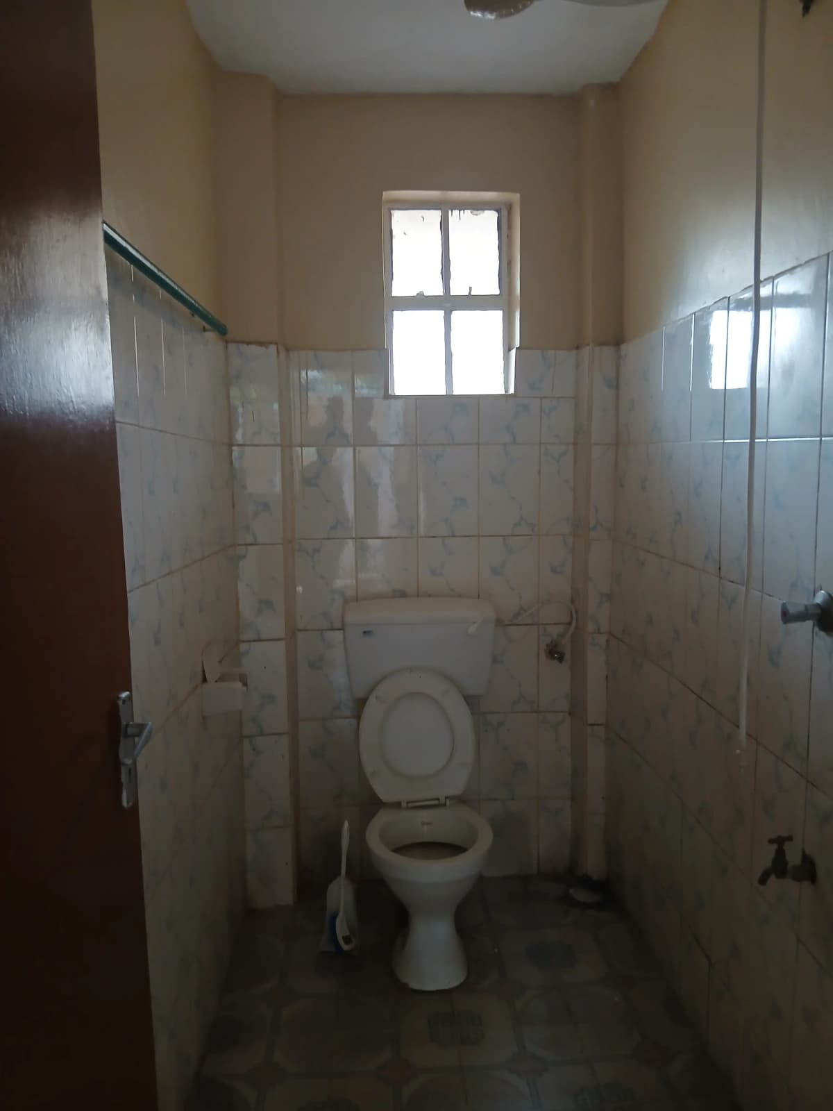 Compact bathroom with toilet, white tile walls, window
