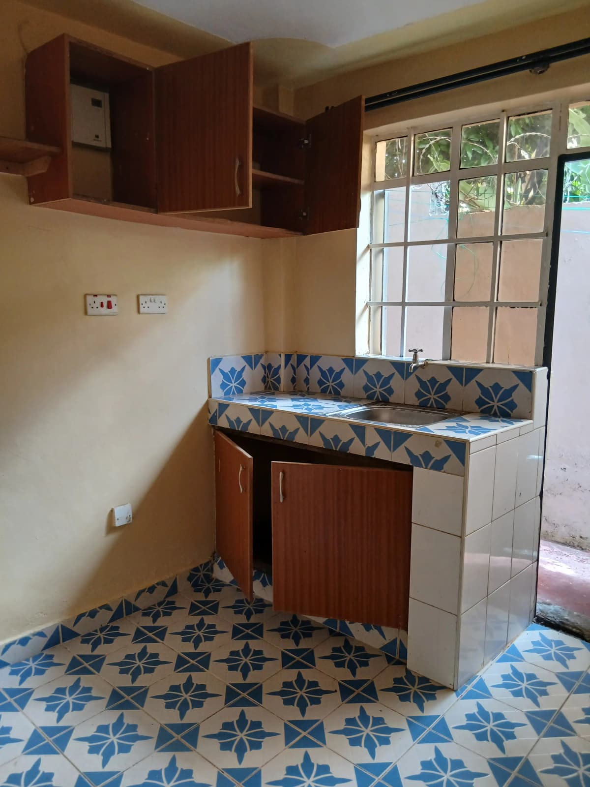 Compact kitchen with wooden cabinets and patterned tile floor