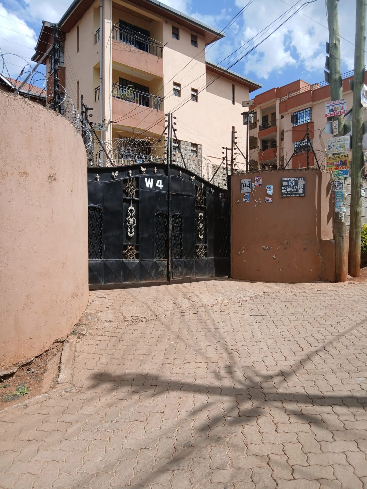 Compound entrance with black metal gate and paved driveway