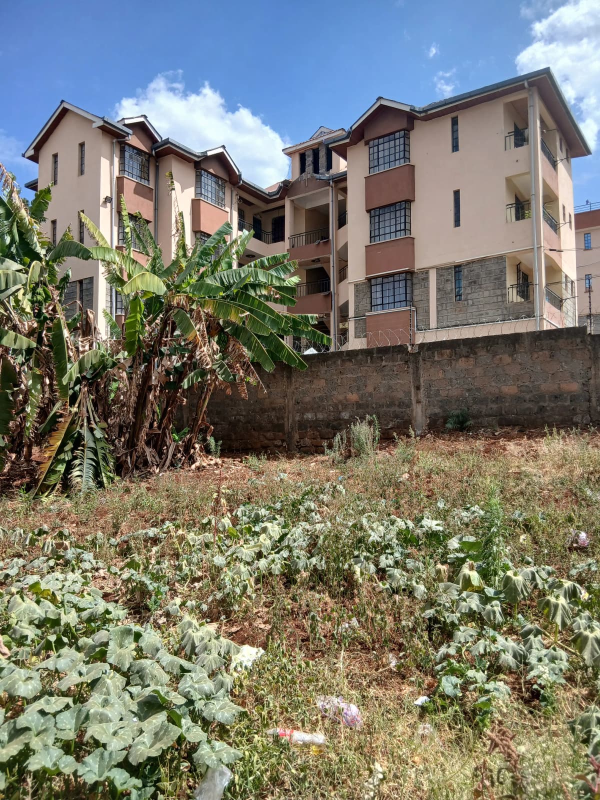 Multi-story residential building with compound grounds and vegetation