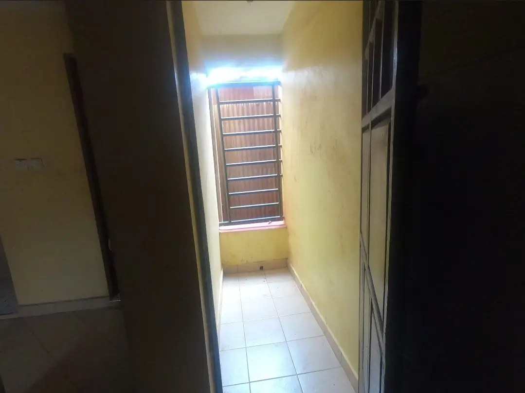Narrow hallway with yellow walls and barred window