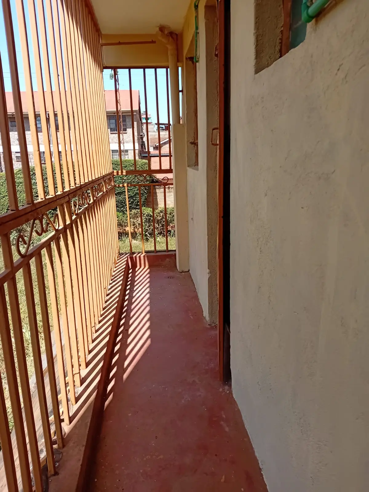 Narrow balcony with metal railing and red flooring