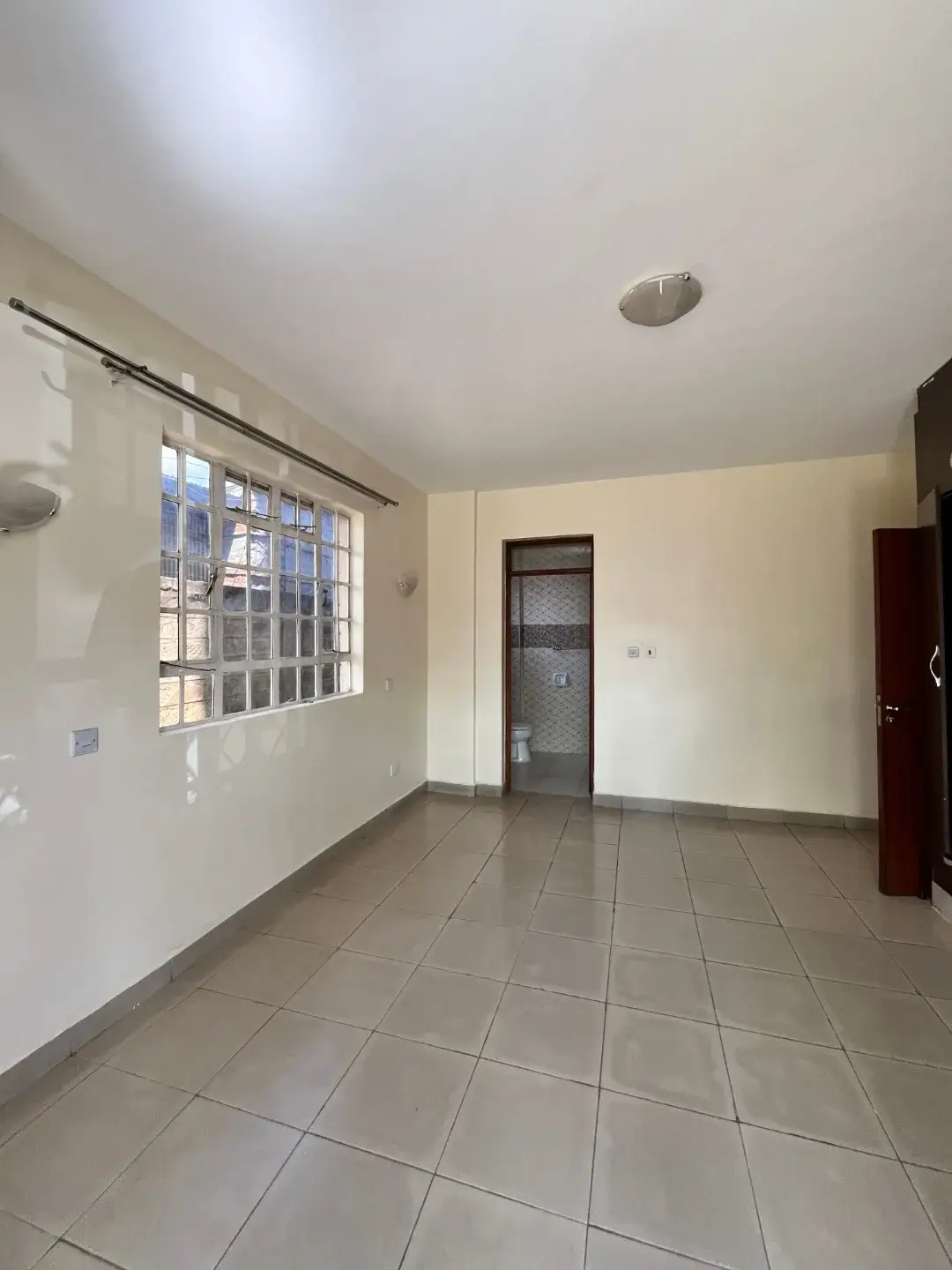 Spacious empty living area with tiled flooring and natural light