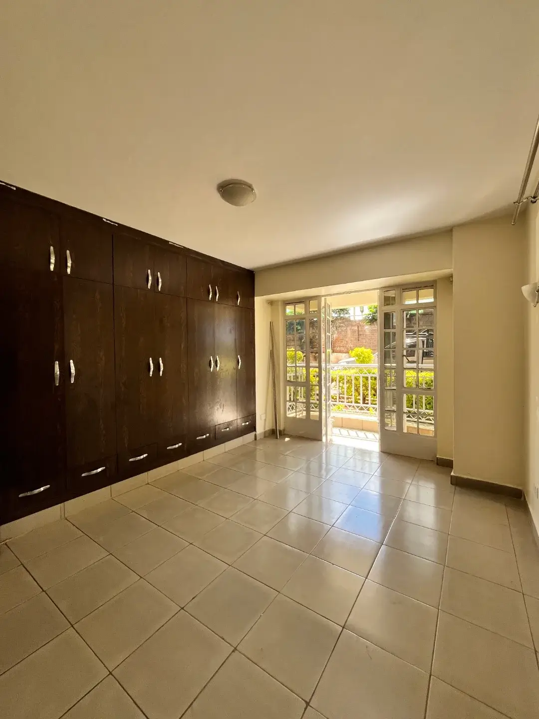 Spacious living area with dark wood built-in wardrobes and glass doors