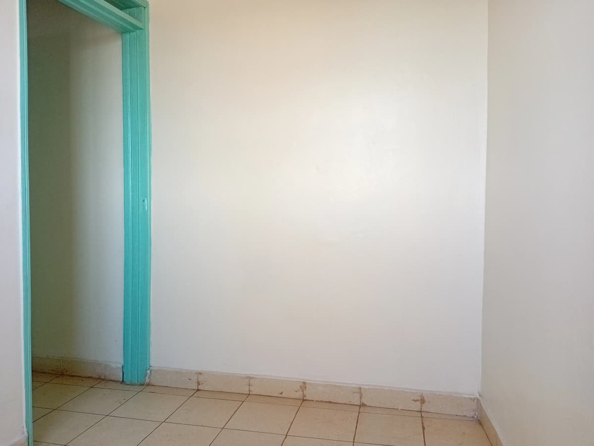 Empty bedroom with turquoise door frame and tiled floor