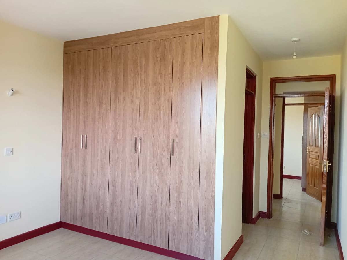 Spacious bedroom with large wooden wardrobe and open doorway