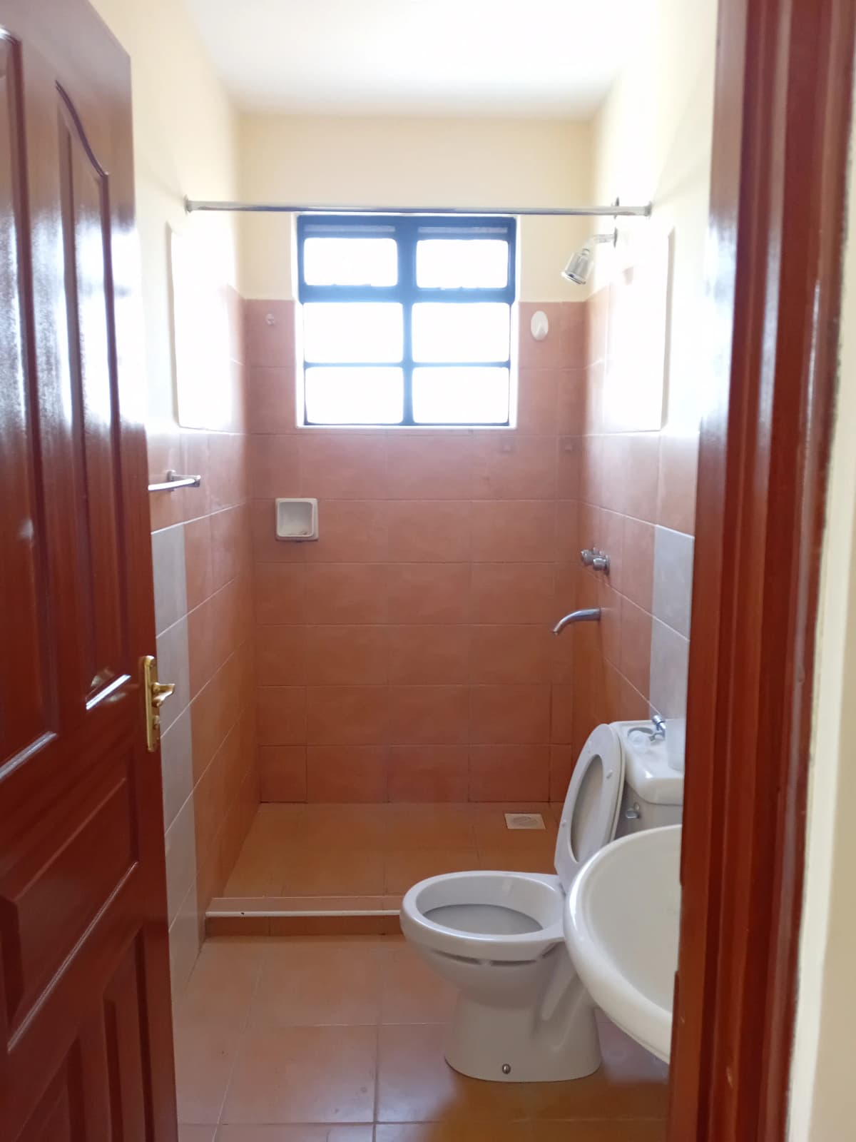 Simple bathroom with toilet, sink, and window