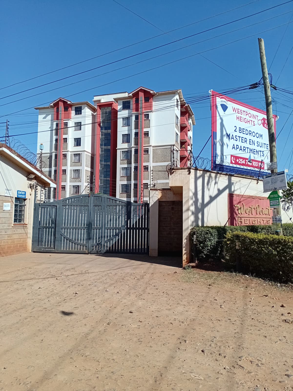 Red and white multi-story residential building with metal gate entrance