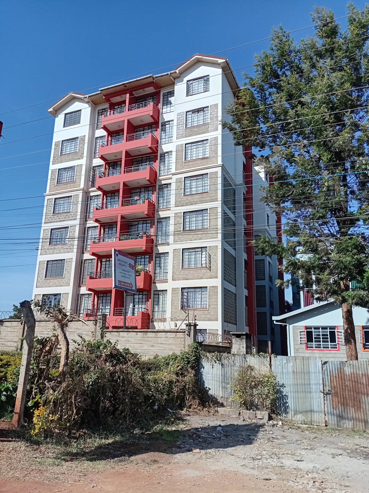 Multi-story residential building with red balconies and white facade